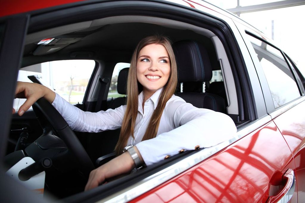 Frau sitzt im Auto und sieht glücklich aus.